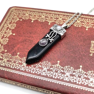 Detailed view of gothic silver necklace with black hexagonal stone and purple crystal