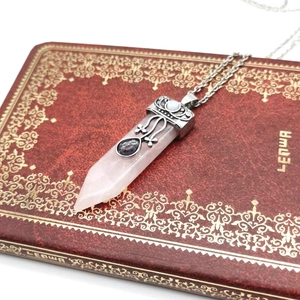 Macro detail of rose quartz hexagonal prism necklace with vintage silver filigree cap