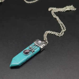 Macro shot of turquoise hex crystal pendant with vintage silver engraving and purple stone