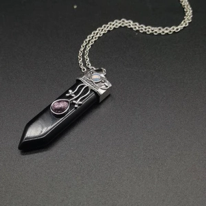 Macro shot of hexagonal black stone pendant with ornate silver metal detailing and small gems