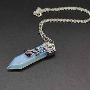 Macro shot of silver-plated sword pendant with opalite gemstone and purple teardrop crystal