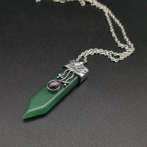 Detail of green hexagonal gemstone pendant with silver metal setting and purple inlay