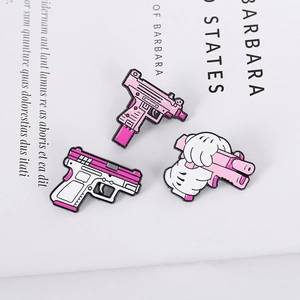 Detailed close-up of cute pink cartoon gun enamel pins with high quality metal finish