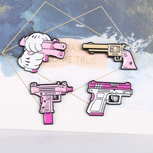 Set of four cute pink cartoon metal pistol brooches on a decorative white card