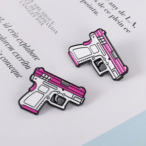 Macro shot of two creative pink and white cartoon pistol enamel pins on a text background