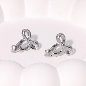 Macro view of polished silver bow stud earrings showing detailed metallic texture