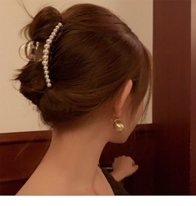Side view of a hair clip with white pearls worn by a model in a warm indoor setting