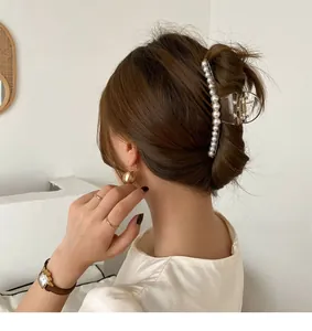 Large pearl hair claw clip in translucent resin shown styling a messy bun hair style