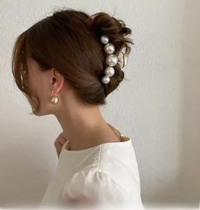 Detailed view of elegant pearl hair claw and matte gold spherical earrings on a model