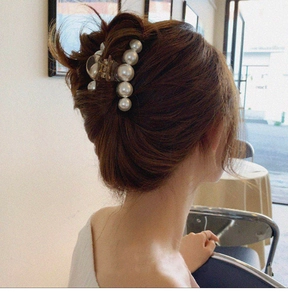 Woman wearing a large white pearl hair claw clip on back of head in a cafe