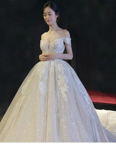 Detail of sequins and lace floral appliques on ivory off-shoulder ball gown wedding dress