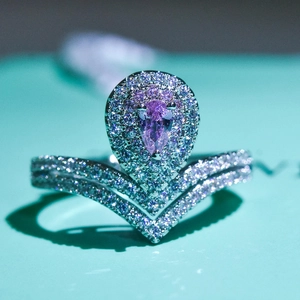 Macro shot of a pear-cut pink gemstone ring with a diamond-studded V-shaped silver band