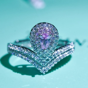 Macro detail of V-shaped ring featuring a pear-cut pink gemstone and pavé diamonds