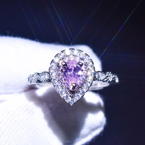 Macro shot of halo pear cut pink moissanite ring with sparkling brilliant light effects