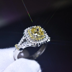 Macro shot of silver ring with yellow cushion cut stone and pavé diamond halo