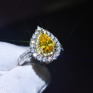 Macro detail of a pear-cut yellow gemstone ring with a luxury double diamond halo setting