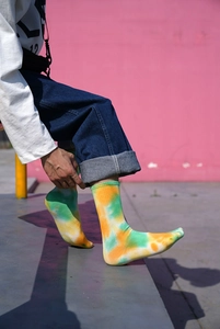 Detail of yellow, green, and orange tie-dye mid-calf socks with ribbed cotton texture