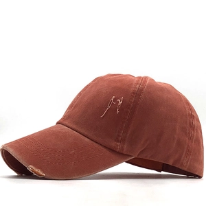 Detail of rust red distressed baseball cap with ponytail hole and washed cotton texture
