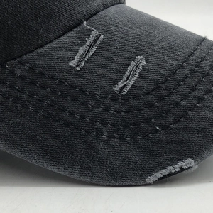 Detailed close-up of distressed brim with torn holes on a washed cotton ponytail baseball cap