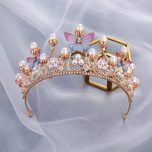 Detailed close-up of a gold princess crown with colorful butterflies and pearls on white tulle