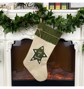 Close-up of linen Christmas stocking with 'Let it Snow' embroidery on a cozy fireplace