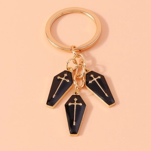 Gothic keychain with black coffin pendants and golden cross details on pink background
