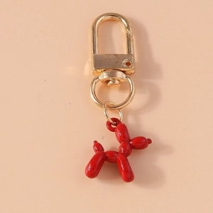 Macro detail of glossy red balloon dog keychain with gold metallic lobster clasp