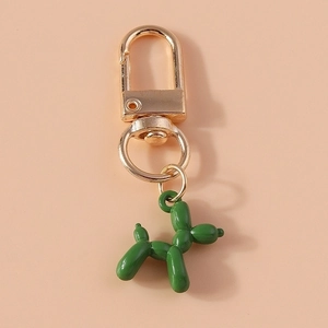 Detail of green balloon dog keychain with golden metal ring on a soft pink background