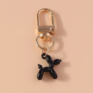 Detail shot of a black glossy balloon dog keychain with a gold metal carabiner