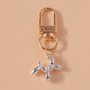 Detail of a bicolored balloon dog keychain with golden lobster clasp and silver pendant