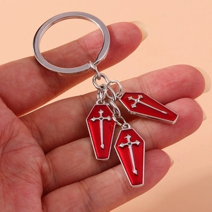 Gothic silver keychain with three red coffin charms and metallic cross details in hand