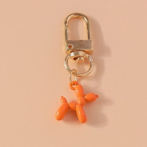 Detailed macro view of orange resin balloon dog keychain with golden polished metal clasp