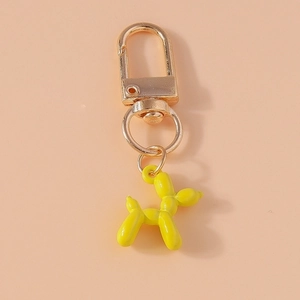 Detail of yellow balloon dog keychain with golden spring buckle on peach background