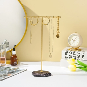 Detail view of T-bar jewelry display with golden metal rod and marble base stand