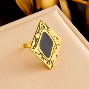 Detail of gold rhombus ring with black enamel inlay on beige leather surface