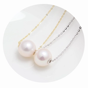 Macro detail of high-luster round white pearl pendants with gold and silver chain necklaces