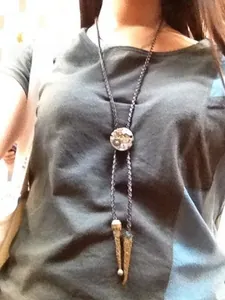 Macro detail of western bolo tie featuring retro mechanical gear motif and braided cord