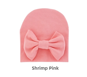 Detail of baby knit hat in shrimp pink with a large bow and soft ribbed texture