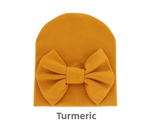 Detail of soft ginger yellow newborn hat with a large decorative bow in ribbed knit