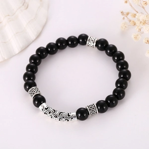 Mens obsidian beaded bracelet with vintage silver hollow metal charms on white background