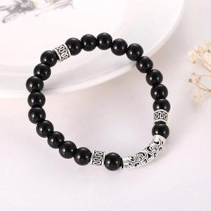 Obsidian beaded bracelet with vintage silver hollow tubes on a decorative ceramic plate