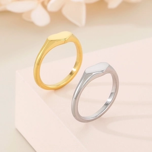 Polished heart signet rings in gold and silver finish on a soft pink display stand
