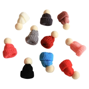 Miniature knitted Christmas hats with pom-poms in various colors on white background