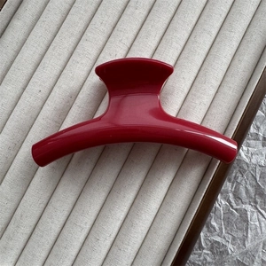 Macro detail of a 11cm red arched hair claw clip on a minimalist display tray