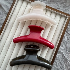 Three minimalist 11cm curved hair claws in white, red, and black in a wooden tray