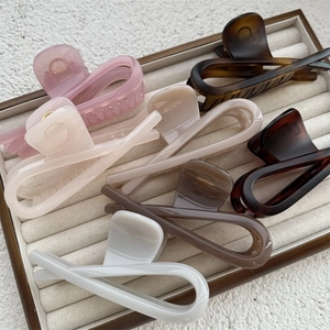 Close-up of large criss-cross hair claws in various colors on a soft velvet jewelry tray