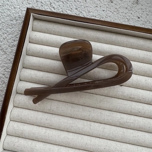 Close-up of a large translucent brown hair claw clip on a beige striped jewelry tray