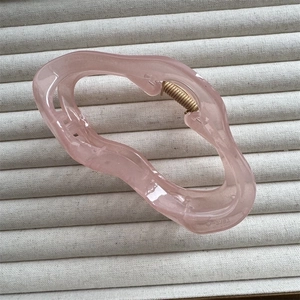 Detailed top view of a large translucent pink cloud-shaped hair claw on a beige texture
