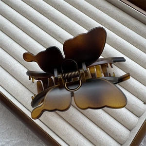 Detailed top view of large amber butterfly hair claw clip with sturdy spring on fabric tray