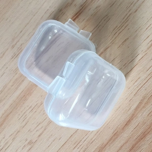 Two small clear plastic square storage boxes with lids on a wooden surface